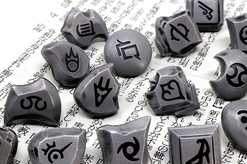 May include: A collection of 14 silver-colored metal tokens with various symbols and designs. The tokens are scattered on a white surface with Japanese text.