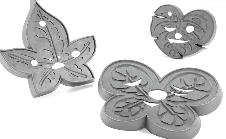 May include: Three gray metal leaf-shaped cookie cutters. The cutters are in the shape of a single leaf, a heart-shaped leaf, and a three-leaf clover.