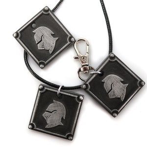 May include: Three silver-toned pendants with a knight's helmet design. The pendants are attached to black cords and one has a silver-toned lobster clasp.
