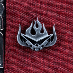 May include: A silver metal pin with a skull wearing sunglasses and a flame design. The pin is on a red fabric background.