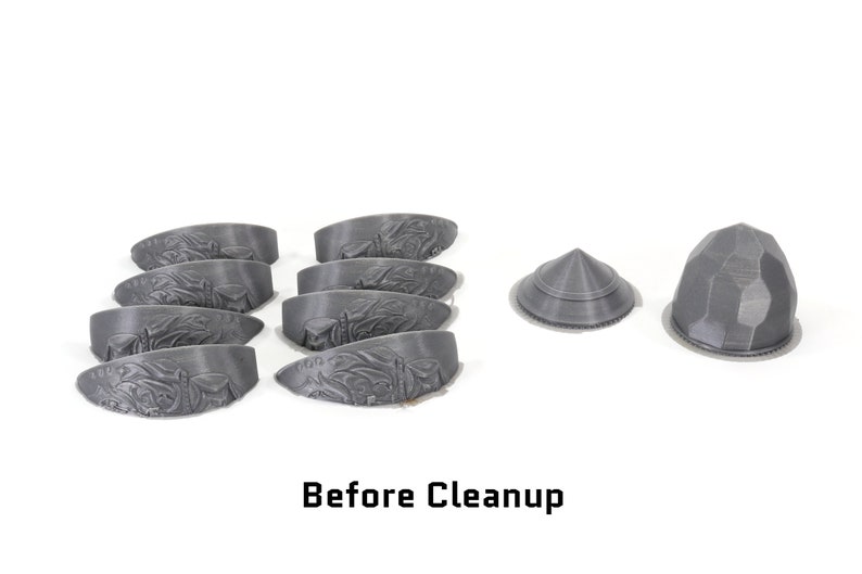 May include: A collection of eight grey 3D printed plastic pieces, including seven curved pieces and two dome-shaped pieces. The pieces are arranged on a white surface. Before Cleanup.