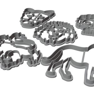 Puede incluir: Conjunto de cuatro cortadores de galletas de metal gris en forma de le&oacute;n, oso, reno y &aacute;rbol de Navidad.