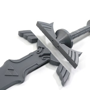 Puede incluir: Una espada de pl&aacute;stico gris con una hoja triangular y un mango con un dise&ntilde;o de alas. La espada est&aacute; desmontada en tres piezas.
