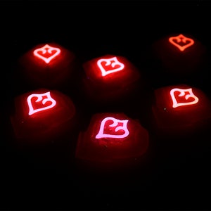 May include: Seven red glowing dice with a white heart symbol on each face. The dice are arranged in a circle on a black background.