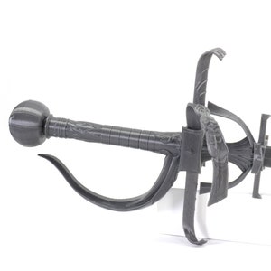 May include: A grey metal sword with a decorative handle and a curved guard. The sword has a black blade and a round pommel.