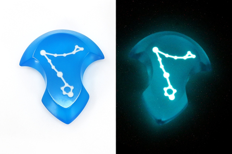 K&ouml;nnte beinhalten: Ein blauer Harz-W&uuml;rfel mit einem wei&szlig;en Sternbild-Design. Der W&uuml;rfel leuchtet im Dunkeln.