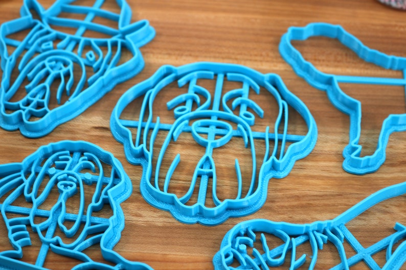 Peut inclure: Un ensemble de cinq emporte-pi&egrave;ces en plastique bleu en forme de diff&eacute;rentes races de chiens. Les emporte-pi&egrave;ces sont sur une surface en bois.