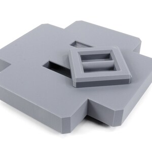 May include: A gray plastic box with a smaller gray plastic box inside. The smaller box has two rectangular openings.