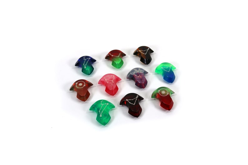May include: Twelve colourful, translucent dice with constellations printed on them. The dice are shaped like a three-pointed star.