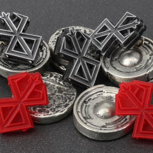 May include: A set of six game pieces, three are silver with a black geometric design and three are red with the same geometric design.