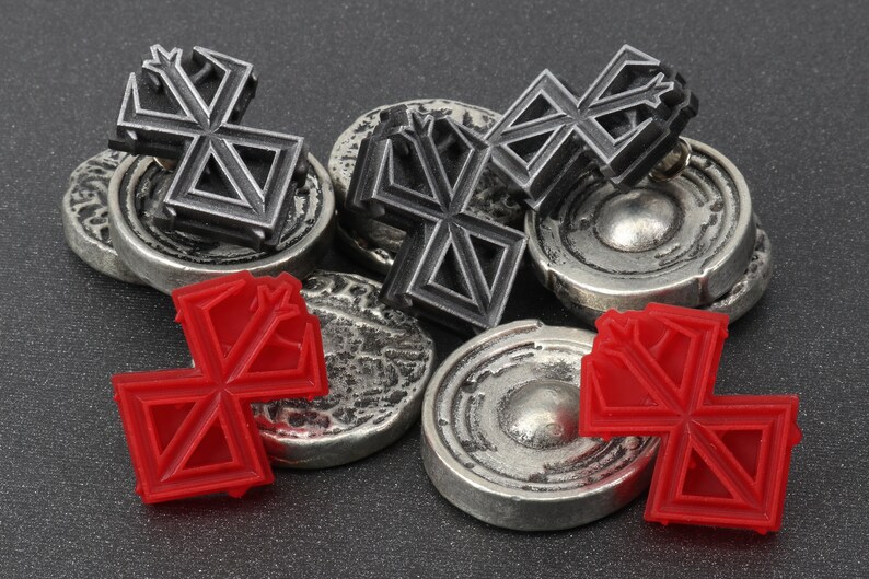 May include: A set of six game pieces, three are silver with a black geometric design and three are red with the same geometric design.