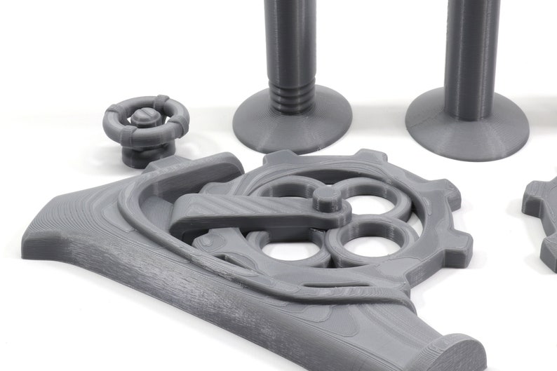 May include: A set of gray 3D printed gears and a lever, with a round knob and two cylindrical bases. The gears are interlocked and have a detailed design.