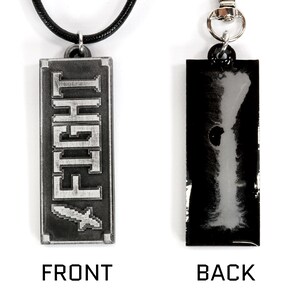 May include: A silver-colored pendant necklace with a black cord. The front of the pendant has the word "FIGHT" in a pixelated font. The back of the pendant is black.