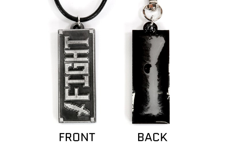 May include: A silver-colored pendant necklace with a black cord. The front of the pendant has the word "FIGHT" in a pixelated font. The back of the pendant is black.