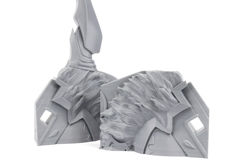 Puede incluir: Dos piezas grises de un modelo impreso en 3D, una con una parte superior puntiaguda y la otra con una superficie texturizada.