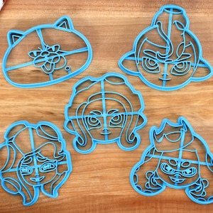 May include: Five blue plastic cookie cutters shaped like characters from the video game Splatoon. The cutters are on a wooden surface.