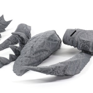 May include: A set of five gray 3D printed dragon pieces, including a head, tail, and wings. The pieces are designed to be assembled into a complete dragon figure.