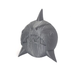 May include: A gray, 3D printed shark figurine with a textured surface and a toothy grin.