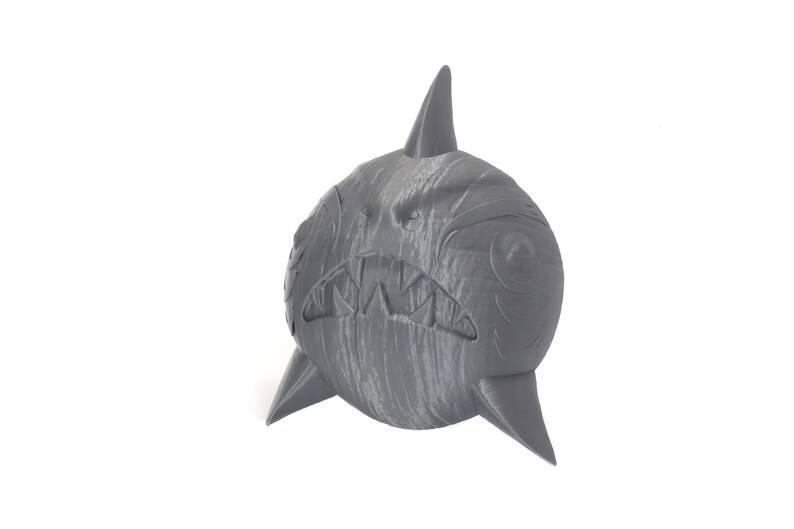 May include: A gray, 3D printed shark figurine with a textured surface and a toothy grin.