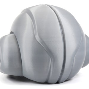 May include: A gray, textured, spherical toy with a smooth, rounded surface. The toy has a unique, futuristic design with a series of ridges and curves.