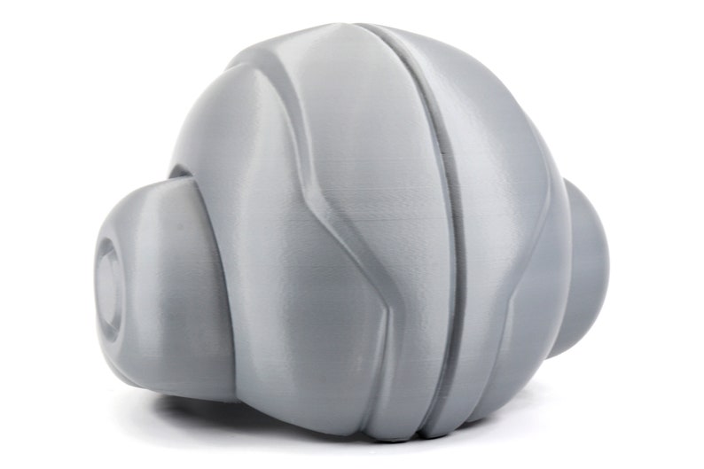 May include: A gray, textured, spherical toy with a smooth, rounded surface. The toy has a unique, futuristic design with a series of ridges and curves.
