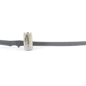 May include: A gray metal sword with a textured handle and a sharp blade. The sword is lying on a white surface next to a can of Japanese beer.