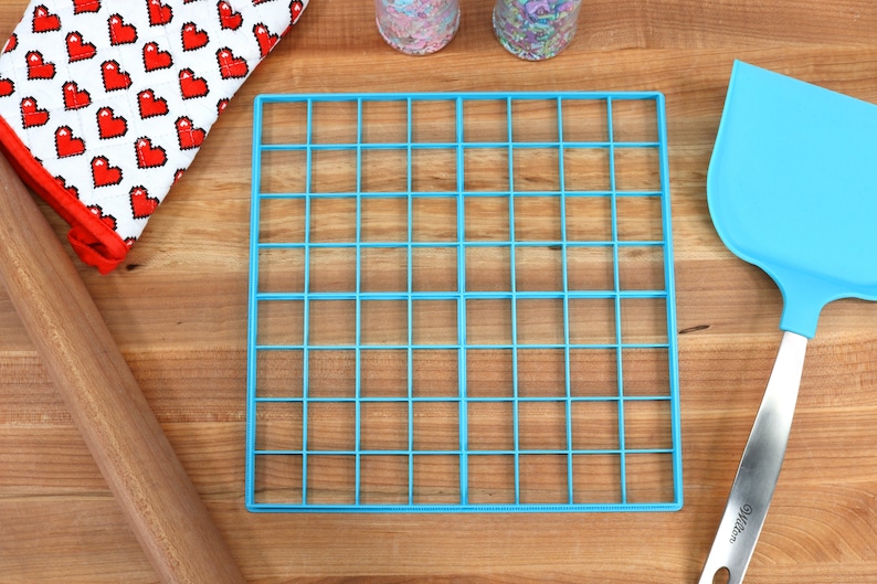 May include: A blue plastic baking grid with 36 squares, a wooden rolling pin, a red and white heart patterned oven mitt, and a blue spatula with a silver handle.