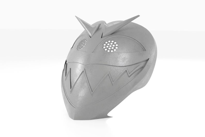 May include: A silver-colored mask with a menacing expression. The mask has a sharp, pointed top and a wide, toothy grin. The eyes are covered with a mesh design.