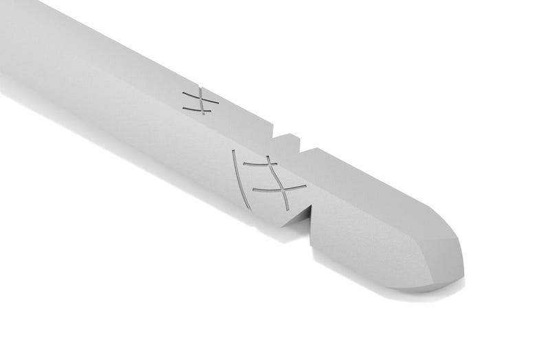 May include: A close-up of a silver metal tool with a pointed tip and a series of crosshatch markings on the side.