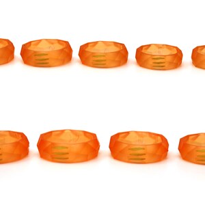 May include: Ten orange plastic rings with a geometric design. The rings have a smooth, glossy finish.