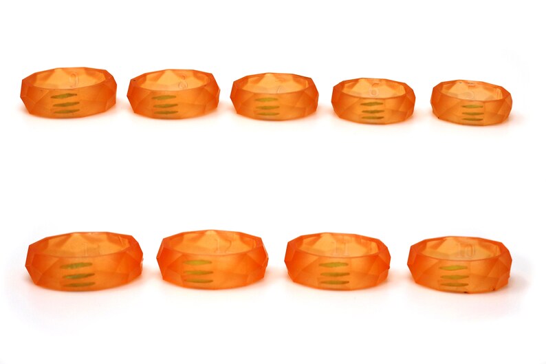 May include: Ten orange plastic rings with a geometric design. The rings have a smooth, glossy finish.