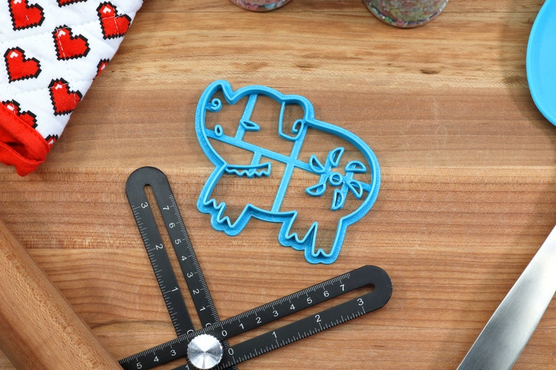 Puede incluir: Un cortador de galletas de pl&aacute;stico azul con forma de rinoceronte con un dise&ntilde;o floral en la espalda.