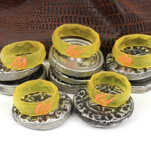 May include: A set of eight yellow silicone rings with a red design. The rings are stacked on top of silver coins.