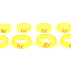 May include: Eight yellow silicone rings with a red logo. The logo is a stylized letter "C" with a small circle inside.