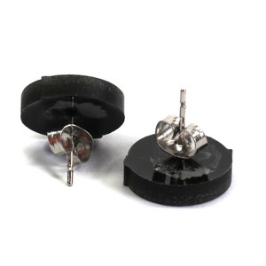 May include: A pair of black stud earrings with silver posts and backs. The earrings are round and have a smooth, polished finish.