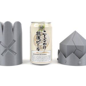May include: Three gray 3D printed objects: a crown, a cylinder with a cross, and a can of beer with Japanese text that reads "Koshihikari Ale Echigo" and "二割三分".