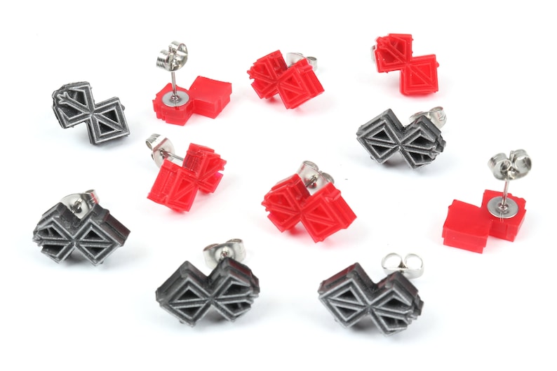 Puede incluir: Un conjunto de ocho pendientes con un dise&ntilde;o geom&eacute;trico. Cuatro pendientes son rojos y cuatro son plateados.