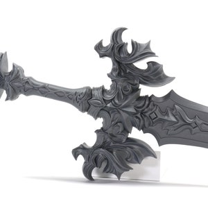 May include: A detailed, ornate, silver-colored sword with a decorative hilt and a sharp blade. The sword is displayed on a white stand.