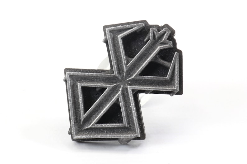 May include: A silver-colored metal ring with a geometric design. The ring is made of multiple layers of metal, creating a three-dimensional effect.