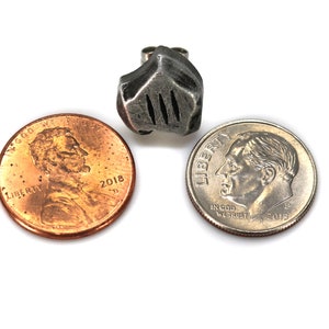 May include: A silver-colored metal earring shaped like a knight's helmet. The earring is shown next to two US coins, a penny and a dime, to show its size.