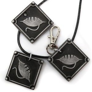Puede incluir: Tres colgantes de metal negro con un dise&ntilde;o de hoja plateada. Cada colgante tiene forma de diamante y est&aacute; unido a un cord&oacute;n negro. Los colgantes est&aacute;n sobre un fondo blanco.