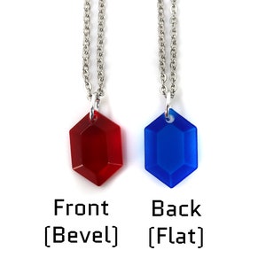 May include: Two necklaces with a red and blue gem pendant. The red gem is beveled and the blue gem is flat. The necklaces are silver chains.