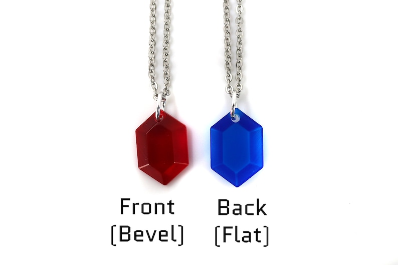 May include: Two necklaces with a red and blue gem pendant. The red gem is beveled and the blue gem is flat. The necklaces are silver chains.
