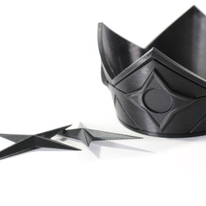 May include: A black plastic crown with a geometric design and a black plastic star-shaped object.