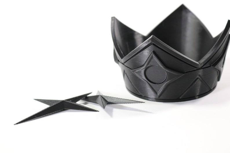 May include: A black plastic crown with a geometric design and a black plastic star-shaped object.