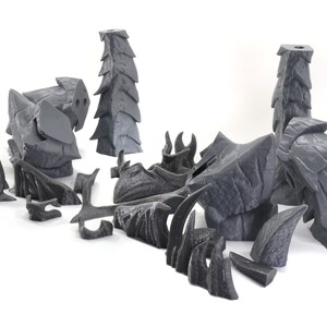 May include: A set of 3D printed, gray, rock-like terrain pieces for tabletop gaming. The pieces are designed to resemble jagged, rocky formations and include a variety of shapes and sizes.