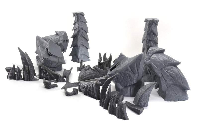 May include: A set of 3D printed, gray, rock-like terrain pieces for tabletop gaming. The pieces are designed to resemble jagged, rocky formations and include a variety of shapes and sizes.