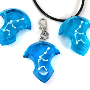 May include: Three blue pendant charms with a white Aquarius constellation design. One charm is on a black cord necklace, and another is on a silver chain with a lobster clasp.