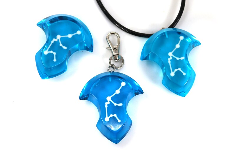 May include: Three blue pendant charms with a white Aquarius constellation design. One charm is on a black cord necklace, and another is on a silver chain with a lobster clasp.