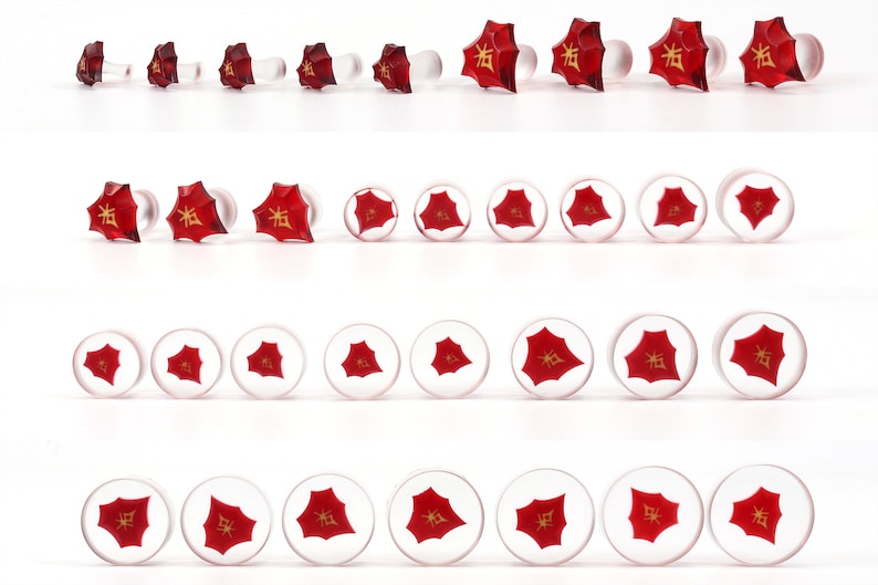May include: A set of 21 red glass plugs with a gold Chinese character on each. The plugs are arranged in three rows, with the largest plugs at the top and the smallest plugs at the bottom.